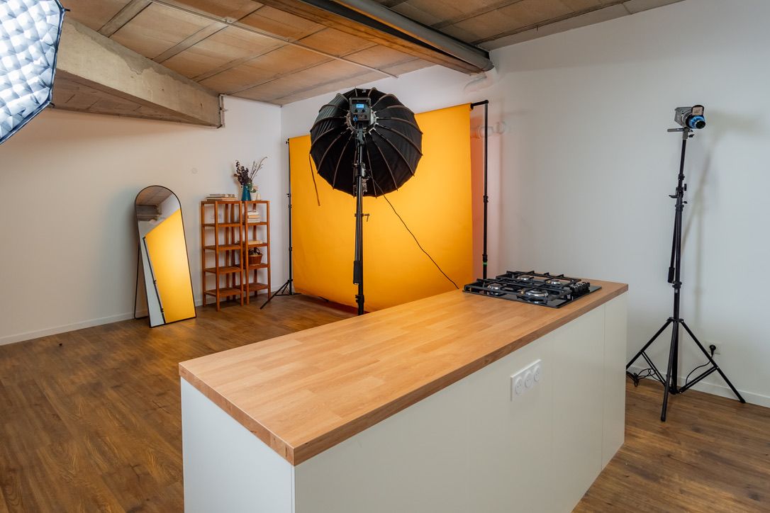Îlot en bois avec plaque de cuisson, projecteur et fond orange dans le studio cuisine de Montreuil