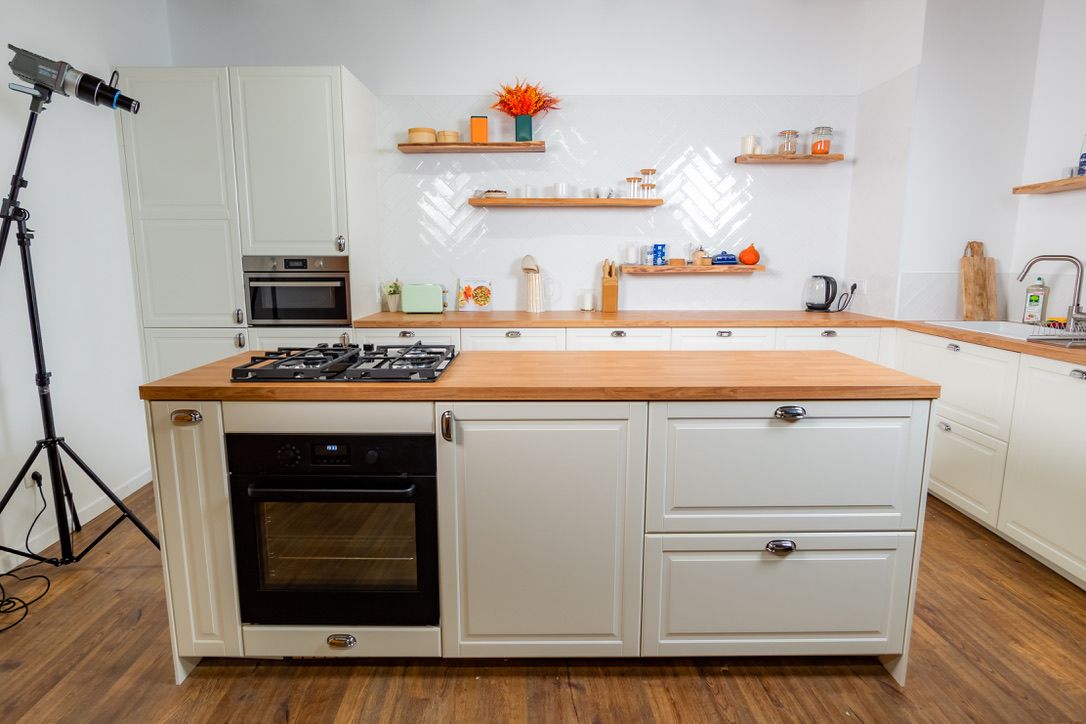 Îlot central du studio cuisine avec plaque de cuisson et four, cuisine blanche en arrière-plan