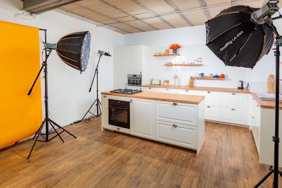 Studio cuisine de Montreuil équipé pour un tournage : îlot avec four, projecteurs et fond orange